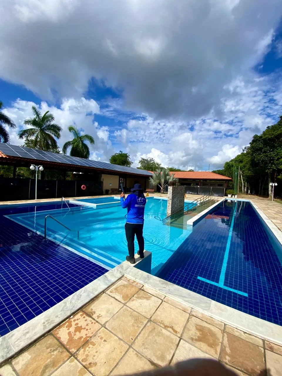 Técnico uniformizado da Celso's Piscinas realizando manutenção em piscina de grande porte